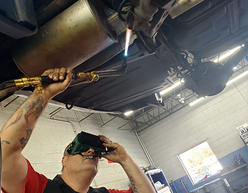 mechanic welding automobile exhaust system photo